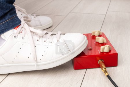 Téléchargez les photos : Un pied de musicien appuyant sur une pédale d'effets rouges lors d'une performance à la maison. - en image libre de droit