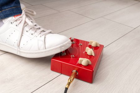 Téléchargez les photos : Un pied de musicien appuyant sur une pédale d'effets rouges lors d'une performance à la maison. - en image libre de droit