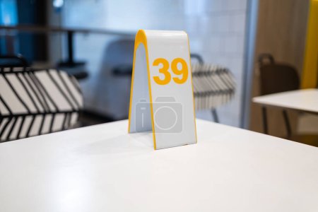 Table number 39 displayed on a white stand with yellow trim, a simple method for service in a modern dining establishment.