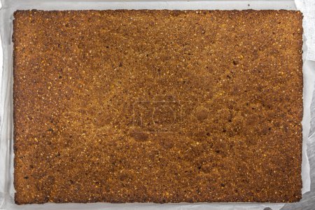 Overhead view of a full tray of uncut muesli fruit bar before slicing, displaying the baked blend of oats, nuts, and fruits.