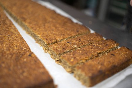 Close-up view of a freshly prepared muesli bar with visible chunks of dried fruit and nuts, showcasing texture and ingredients.