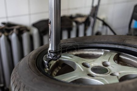 Una vista de cerca que muestra el proceso de debeading un neumático de coche, con herramientas de metal y detalles del taller.