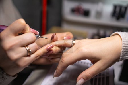 Foto de Una manicura que aplica un diseño meticuloso a las uñas de un cliente, con un enfoque en la precisión y el proceso de belleza. - Imagen libre de derechos