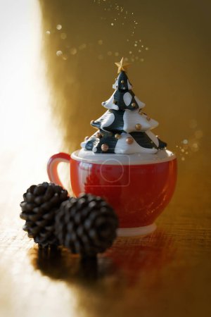 Téléchargez les photos : Image d'un arbre de Noël poussant dans une tasse de café recouverte de neige sucrée sur un fond doré scintillant, cônes de pin, faible profondeur de champ - en image libre de droit