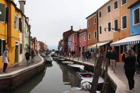Photo for BURANO, ITALY - APRIL 29, 2019: Burano island, typical street canal and multi-colored houses of locals. Burano the island - one of famous tourist objects in the Venetian lagoo - Royalty Free Image