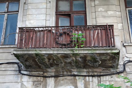 Ein verlassenes Haus mit heruntergekommenem Balkon und verrostetem Geländer 