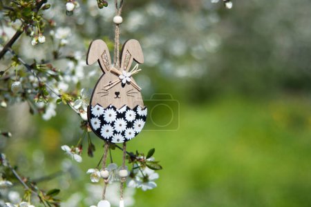 Photo for Greeting card with space for text. Easter decor. Decorative wooden Easter bunny toy on background of blooming spring garden. Outdoor - Royalty Free Image
