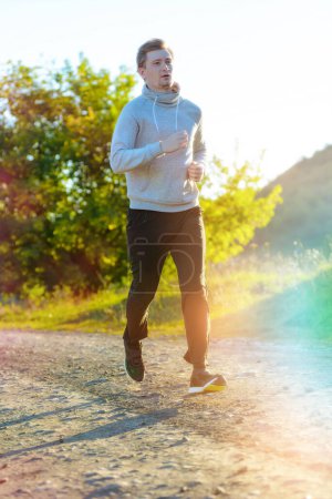 Foto de Hombre corriendo corriendo corriendo en la naturaleza rural en un hermoso día de verano. Deporte fitness modelo caucásico etnia entrenamiento al aire libre. - Imagen libre de derechos