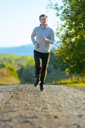 Téléchargez les photos : Courir homme jogging dans la nature rurale à la belle journée d'été. Sport fitness modèle caucasien ethnicité entraînement de plein air. - en image libre de droit