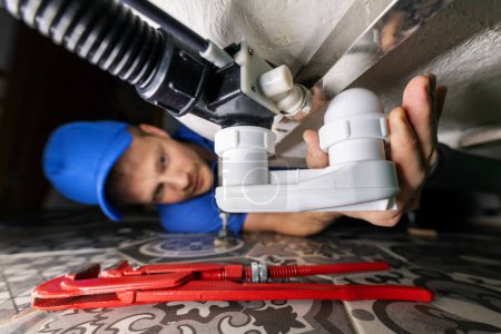 Téléchargez les photos : Plumbing service. plumber at work in bathroom. repair and install drain siphon under the bath - en image libre de droit