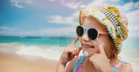 Téléchargez les photos : Enfant mis sur la crème solaire sur le visage à la plage. protection de la peau des coups de soleil. bannière avec espace de copie - en image libre de droit