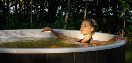 Foto de Mujer relajándose en la bañera de hidromasaje del bosque al atardecer. spa de naturaleza. banner con espacio de copia - Imagen libre de derechos