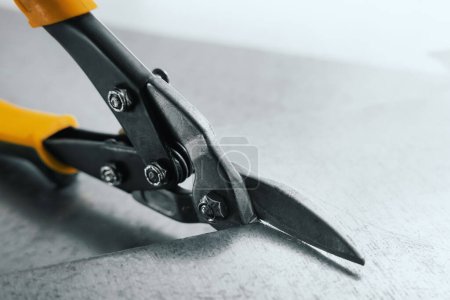 Photo for Closeup of metal scissors cutting a tin sheet - Royalty Free Image