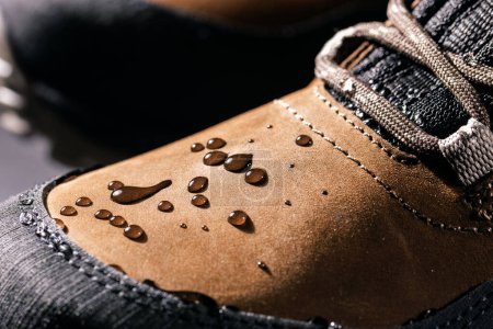 Téléchargez les photos : Bottes en cuir imperméables. gros plan de gouttes de pluie sur des chaussures imperméables. vêtements résistant aux intempéries - en image libre de droit