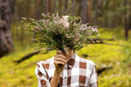 Foto de Mujer en el bosque sosteniendo ramo de brezo en frente de su cara - Imagen libre de derechos