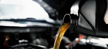 Foto de Mecánico verter aceite de motor de botella en el motor en el taller de reparación de automóviles. banner con espacio de copia - Imagen libre de derechos