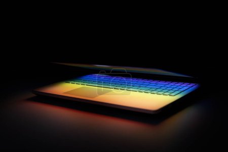 Foto de Portátil medio cerrado en la mesa oscura con reflejo de luz de colores en el teclado - Imagen libre de derechos