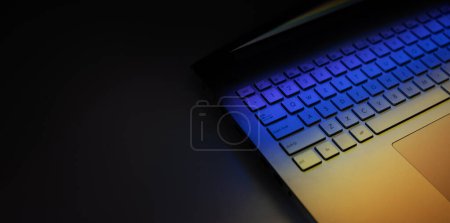 Foto de Primer plano del teclado del ordenador portátil en la mesa oscura con reflejo de luz de colores. banner con espacio de copia - Imagen libre de derechos