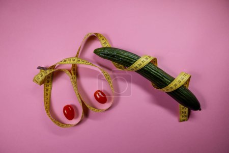 Foto de Size of the breast and penis concept. cucumber with tomatoes and measuring tape - Imagen libre de derechos