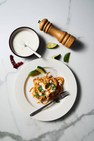 Photo for Top view of Plate with Mexican pasta. Pasta with tomato sauce with chilli puree, feta and cream cheese. Spaghetti macaroni boiled al dente and mixed with sauce. High quality photo - Royalty Free Image