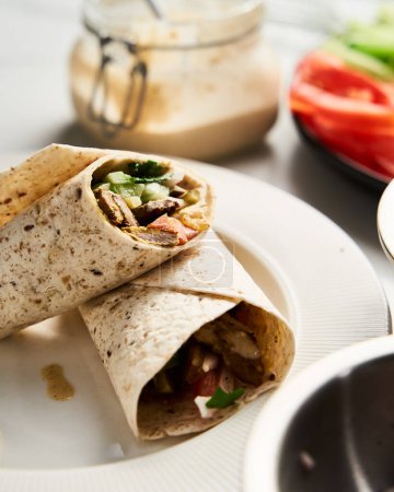 Photo for Beef and Lamb Lebanese style shawarma with onions, greens and vegetables such cucumber and tomato. all seasoned with tahini and garlic sauce and wrapped in pita or pita bread. High quality photo - Royalty Free Image
