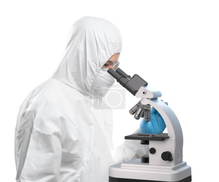 Foto de Worker wears medical protective suit or white coverall suit with mask and goggles look through microscope isolated on white background - Imagen libre de derechos