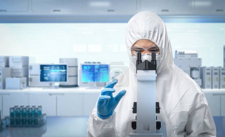 Photo for Worker wears medical protective suit or white coverall suit with mask and goggles look through microscope in laboratory - Royalty Free Image