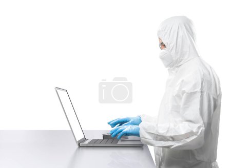 Téléchargez les photos : Travailleur porte une combinaison de protection médicale ou combinaison blanche travail avec ordinateur portable isolé sur fond blanc - en image libre de droit