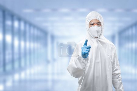Téléchargez les photos : Worker wears medical protective suit or white coverall suit with mask and goggles finger point - en image libre de droit
