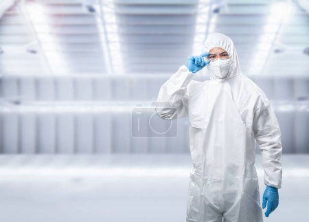 Foto de Worker wears medical protective suit or white coverall suit with mask and goggles - Imagen libre de derechos