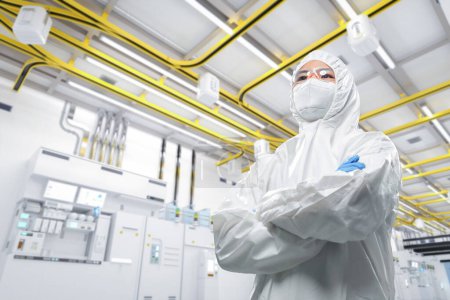 Foto de Trabajador o ingeniero usa traje protector o traje de mono blanco en fábrica de fabricación de semiconductores - Imagen libre de derechos