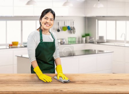 Téléchargez les photos : Asiatique femme de ménage porter des gants en caoutchouc jaune et vert tablier essuyer table - en image libre de droit