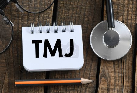 Mots TMJ (joints temporomandibulaires) dans un petit carnet de notes de bureau.