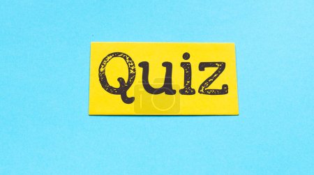 Quizzeitkonzept, Wort auf kleinem Blatt Papier und blauem Hintergrund.