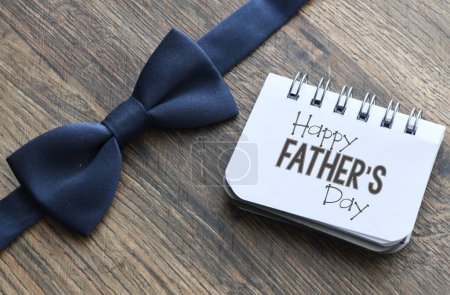 Photo for Happy Father's Day text on notepad and wooden background. Greetings and presents - Royalty Free Image