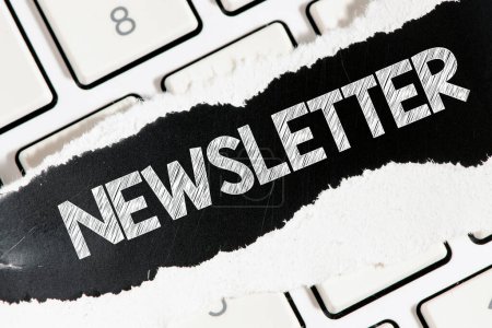The word newsletter written on a black piece of paper located on a white keyboard. 