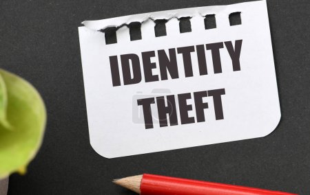 IDENTITY THEFT words on a piece of paper and a black table.