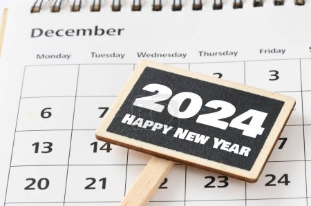 Happy new Year 2024 words on a small chalk board and calendar.