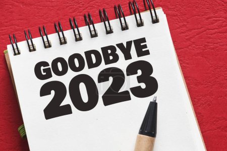 Photo for GOODBYE 2023 text in an office notebook on a red table. - Royalty Free Image