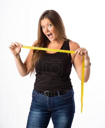 Photo for Isolated portrait of a forty year old woman wearing a tank top, holding a yellow mesuring tape, with a surprise expression - Royalty Free Image