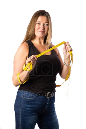 Photo for Isolated portrait of a forty year old woman, wearing a black tank top, holding a yellow mesuring tape at the ready - Royalty Free Image