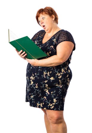 Photo for Fifty year old overweight woman, looking into a large green book, with surprise expression, against a isolated white background - Royalty Free Image