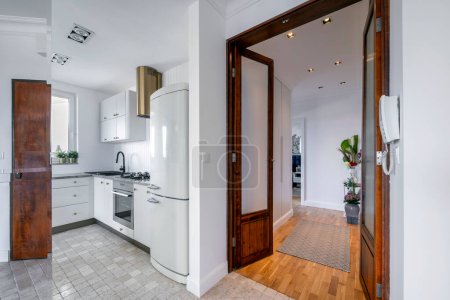 Téléchargez les photos : Cuisine blanche moderne design intérieur et couloir avec portes en bois - en image libre de droit