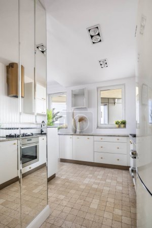 Téléchargez les photos : Intérieur élégant et moderne d'espace ouvert cuisine blanche et mur miroir. Conception concept de décoration à la maison - en image libre de droit