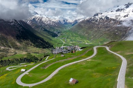The alpine village of Andermatt surrounded by green meadows, and snowy peaks in the background, Canton of Uri, Switzerland, Europe