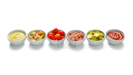 Foto de Fila de tazones de verduras con pepinos, ketchup, tomates, mostaza, coliflor, col - Imagen libre de derechos