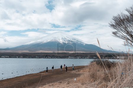 Photo for Tourist walking on the shore of Yamanaka lake with Mt. Fuji background on cloudy day - Royalty Free Image