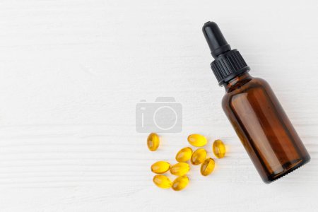 Photo for D3 vitamin in bottle and oil soft gel capsules on a white wooden table, top view - Royalty Free Image
