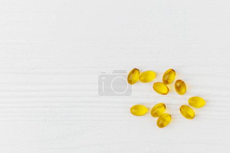 Oil soft gel capsules on white wooden table, top view