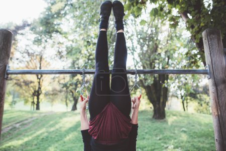 Photo for Unknown sportive fit young woman practicing workout for strength and balance in an outdoor fitness park - Royalty Free Image